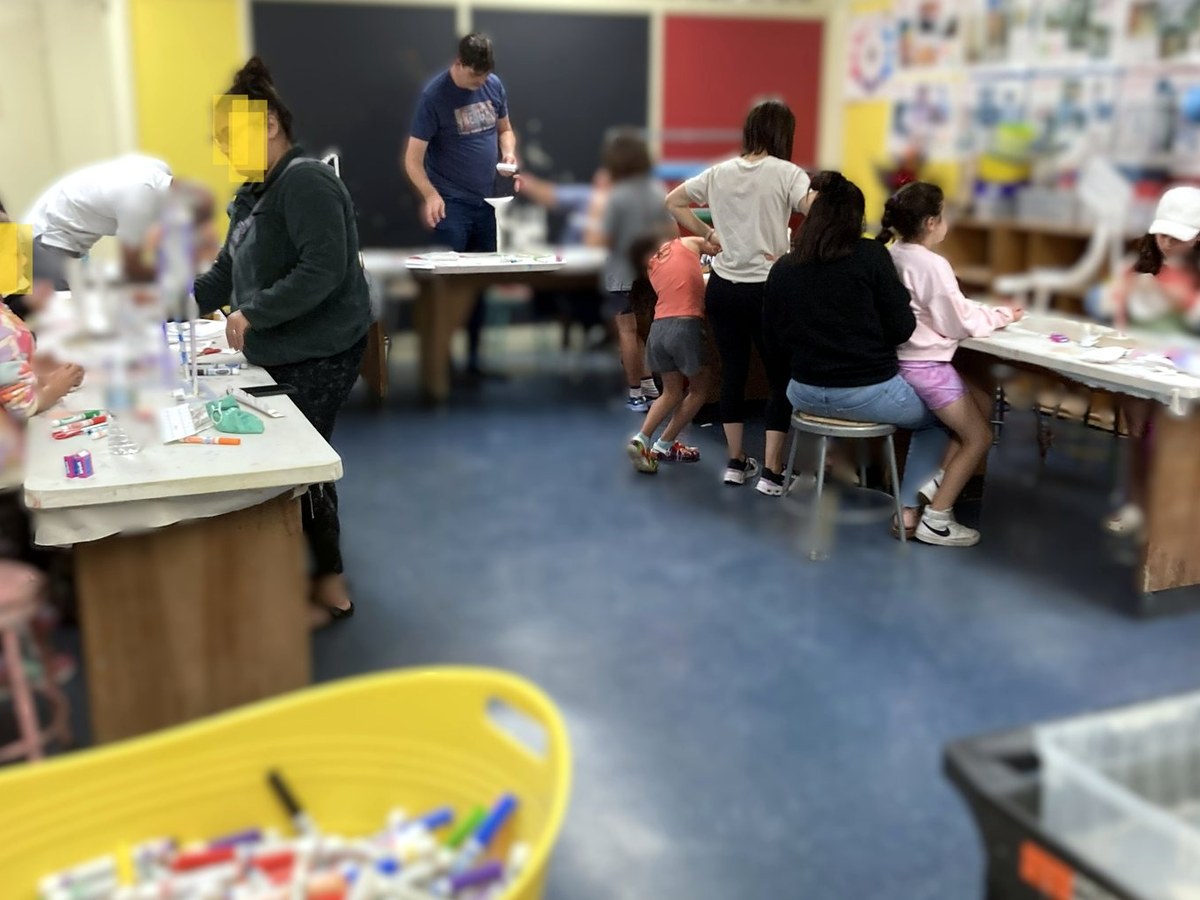 Participants working together around tables in an active art classroom.