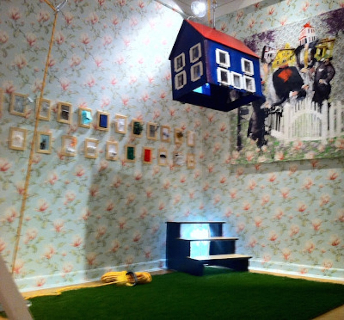 HomeSweetHouse installation with a suspended blue house, patterned walls, and green floor.